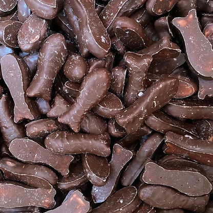 A pile of classic bite sized raspberry chewy fish lollies coated in a smooth milk chocolate layer