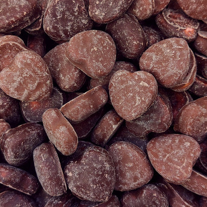 A pile of red strawberry flavored chew heart lollies coated in smooth milk chocolate
