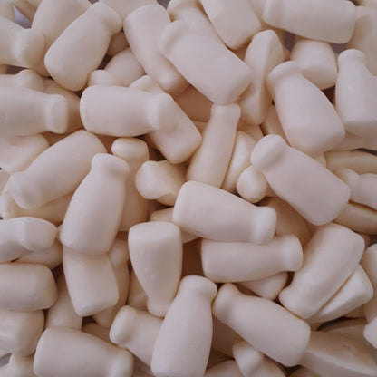 A close up of opaque white bottle shaped aerated gummy milk bottle lollies