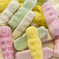 A colorful assortment of eskimo shaped grained marshmallow emo lollies in yellow pink and green