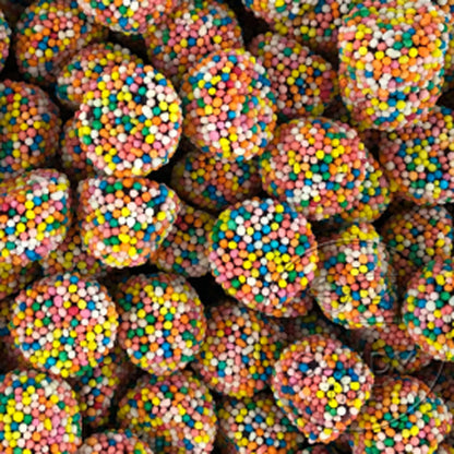 A pile of dome shaped licorice flavored jelly lollies completely coated in colorful hundreds and thousands sprinkles